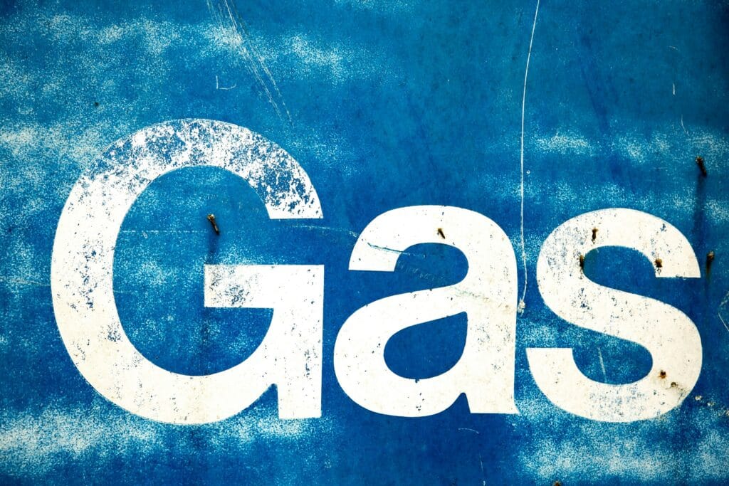 Weathered blue metal sign with the word Gas painted in large white letters