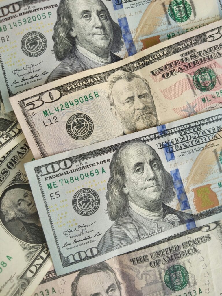 Various U.S. dollar bills spread out, including $100, $50, and $1 denominations, illustrating household income and budgeting concepts
