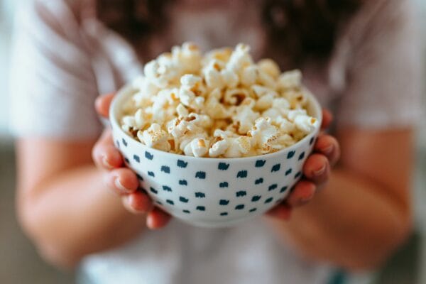 Bowl of popcorn held in hands after getting a dental crown