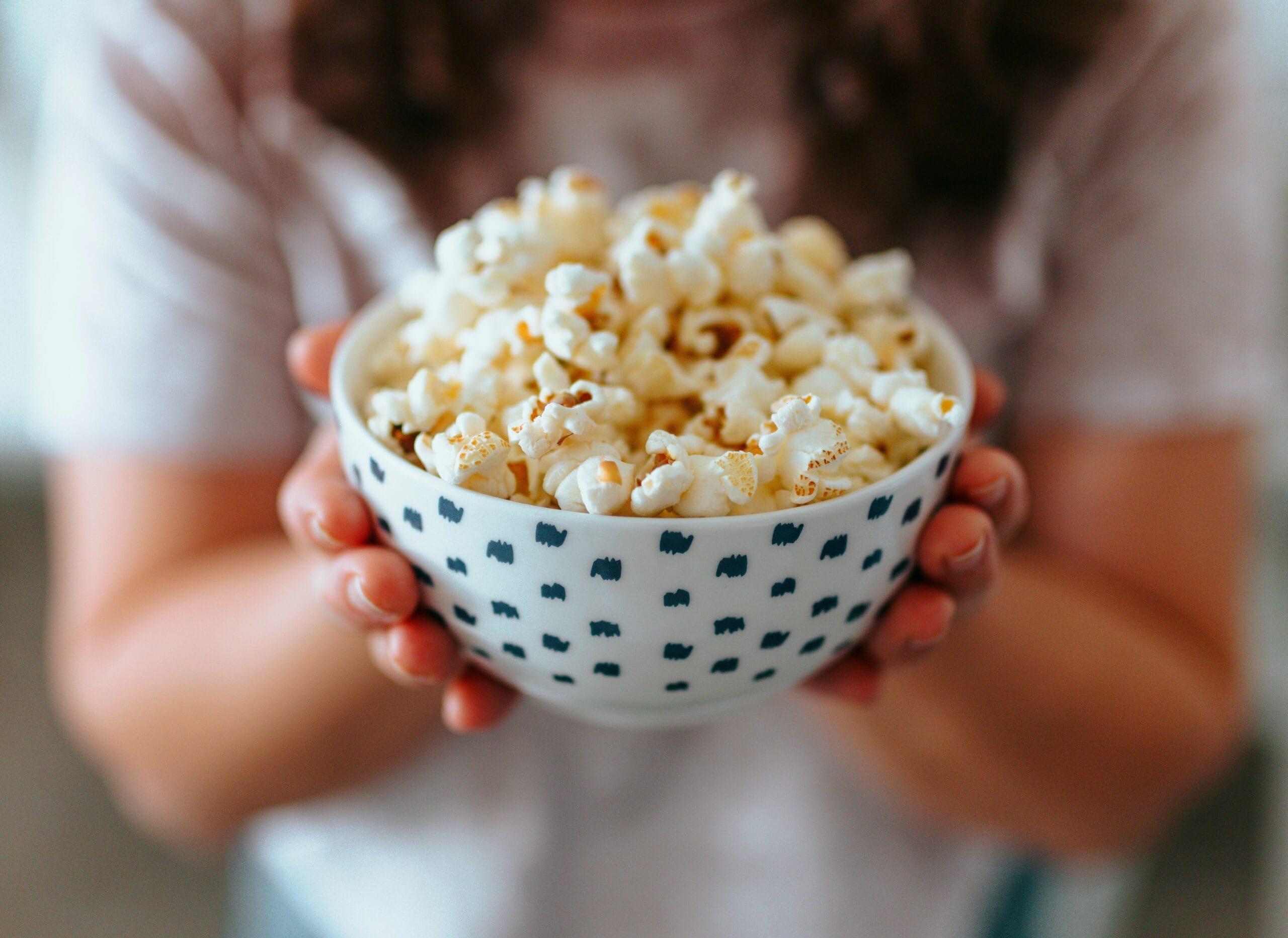 Bowl of popcorn held in hands after getting a dental crown