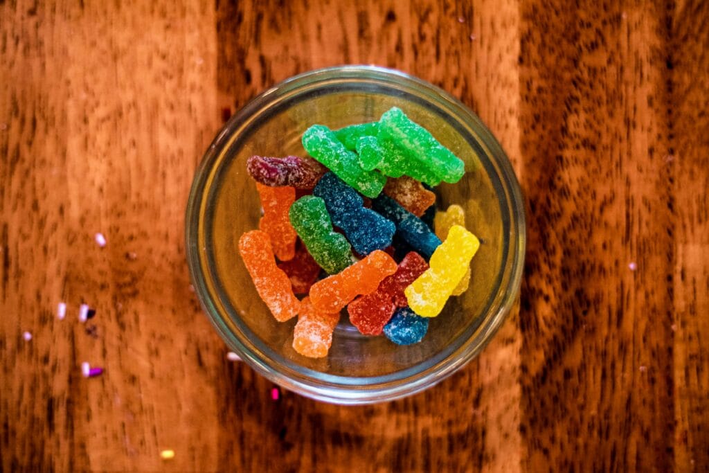 Colorful sugar-coated gummy candies in a glass bowl — a sticky food to avoid after dental crown placement