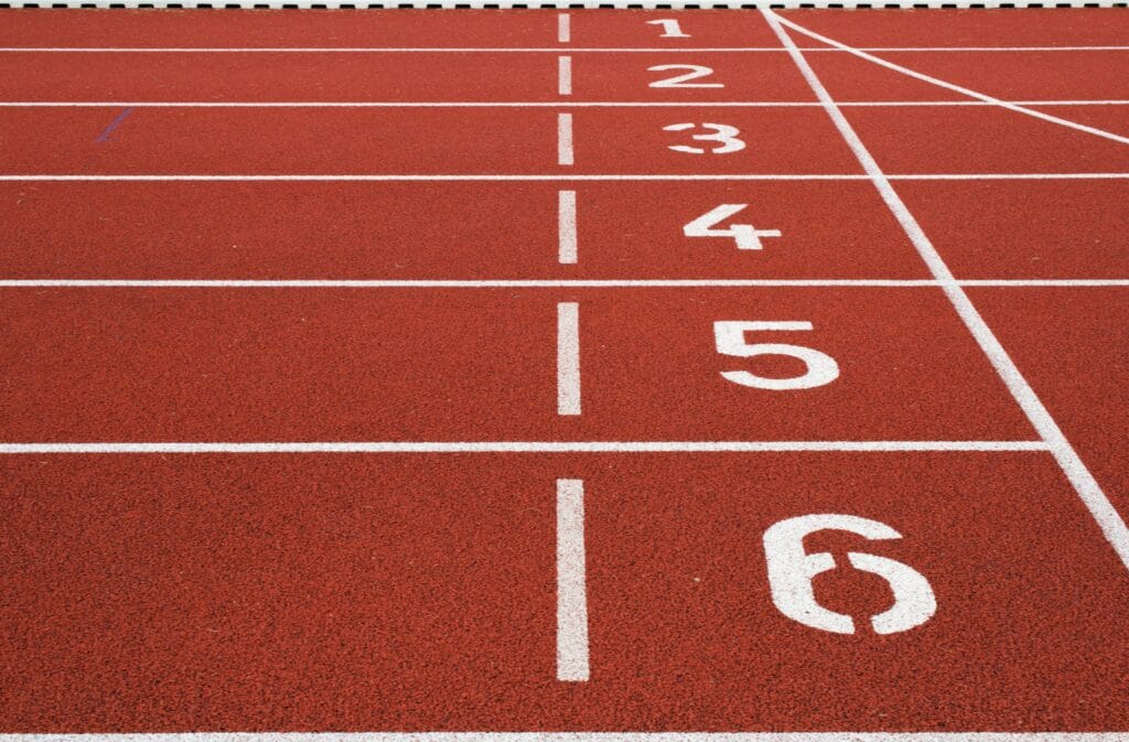 Numbered lanes 1 through 6 on a red running track, representing the structured progression of a beginner running plan