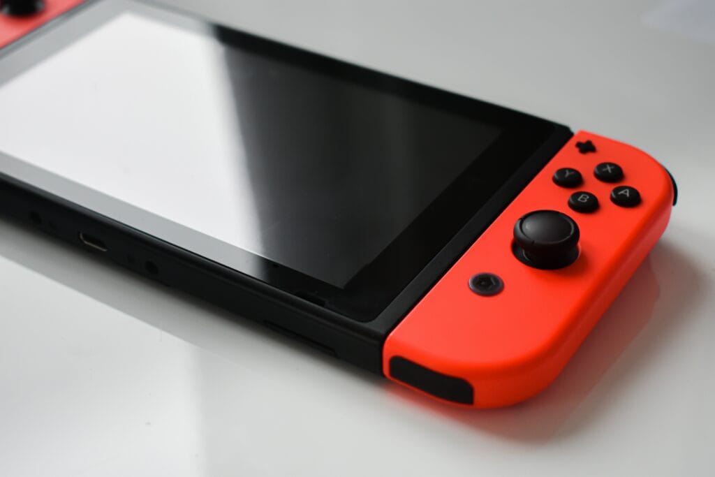 Nintendo Switch console with neon red Joy-Con controller attached, screen off, resting on a flat surface