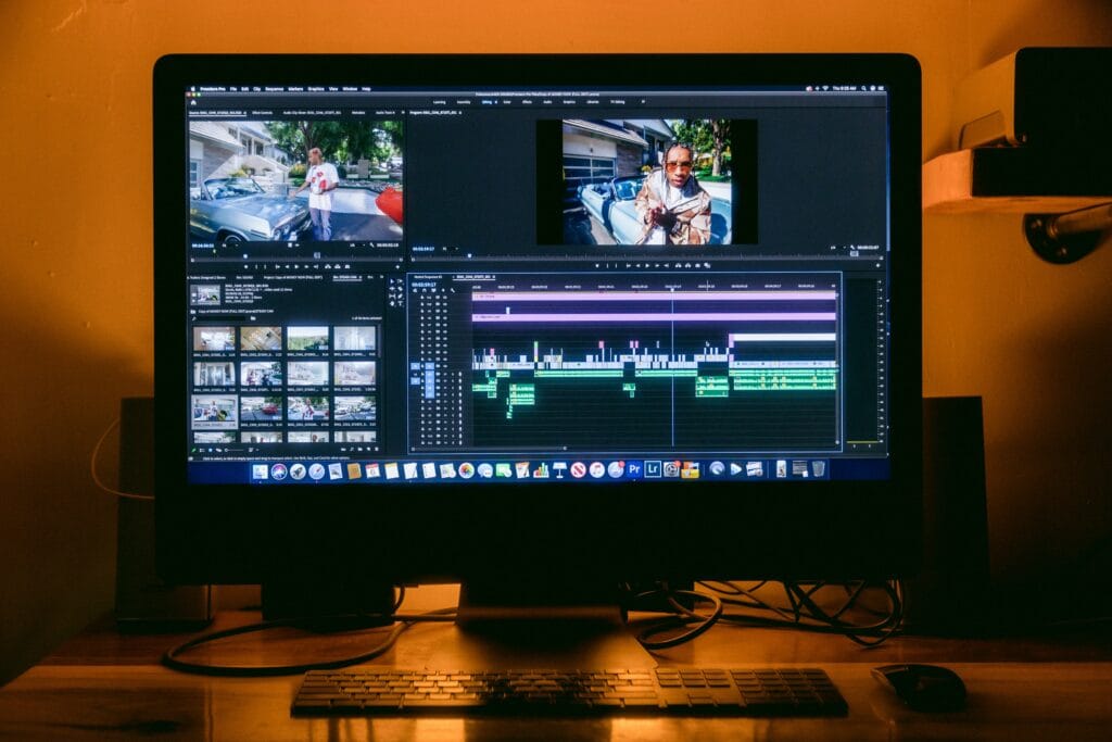 Adobe Premiere Pro open on a desktop monitor showing a multi-track timeline, source and program preview panels, and a media bin with video clips