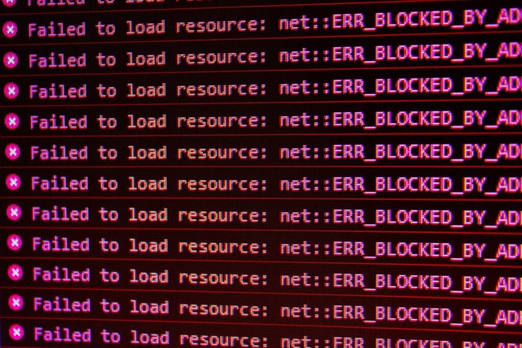 Browser console filled with repeated red error messages reading "Failed to load resource: net::ERR_BLOCKED_BY_AD", illustrating network-level blocking of unauthorized requests